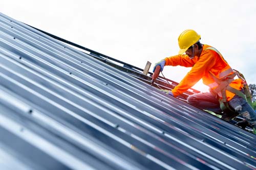Team member installing roofing on commercial building at sunrise