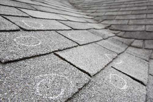 Closeup of hail damaged shingles circling the damage.